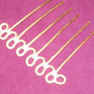 May include: Gold hair comb with a decorative design of interlocking loops. The comb has seven tines.