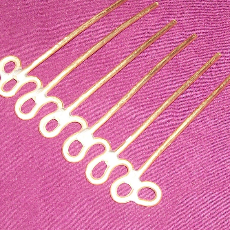 May include: Gold hair comb with a decorative design of interlocking loops. The comb has seven tines.