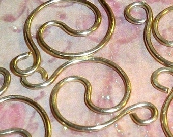 Könnte beinhalten: Goldfarbene Metalldrahtschlaufen in einem wirbelnden Muster. Die Schlaufen sind miteinander verbunden und bilden ein dekoratives Design.