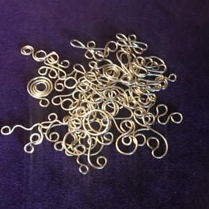 May include: A collection of silver wire swirls and loops, arranged in a random pattern on a purple background.