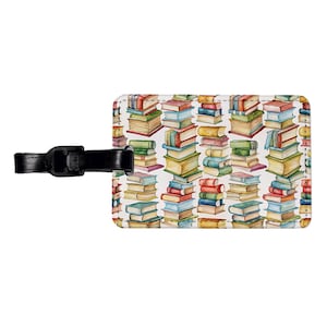 May include: A luggage tag with a white background and a colorful pattern of stacked books. The tag has a black strap.
