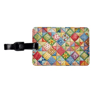 May include: A colorful luggage tag with a patchwork design featuring various shades of red, blue, green, yellow, and white. The tag has a black leather strap with a buckle.