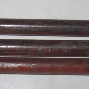 May include: Three dark brown, cylindrical objects with a reddish hue, possibly wooden dowels or rods, are arranged horizontally. The objects have a slightly rough texture and appear to be used for construction or crafting.