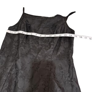 May include: Black lace dress with spaghetti straps. The dress is measured at 14 inches across the chest. The dress has a floral lace pattern and a fitted bodice.