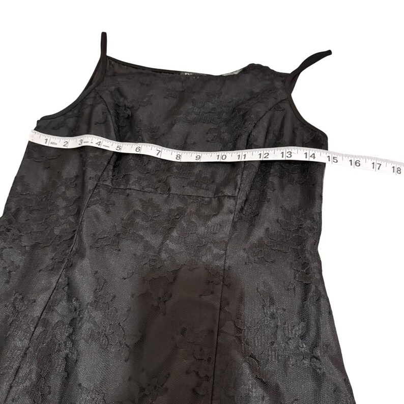 May include: Black lace dress with spaghetti straps. The dress is measured at 14 inches across the chest. The dress has a floral lace pattern and a fitted bodice.