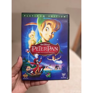May include: A Walt Disney Peter Pan 2-Disc Platinum Edition DVD case featuring a blue background with illustrations of Peter Pan, Tinker Bell, Captain Hook, Wendy, and a crocodile. The text reads Platinum Edition, Walt Disney's Peter Pan, and 2-Disc.