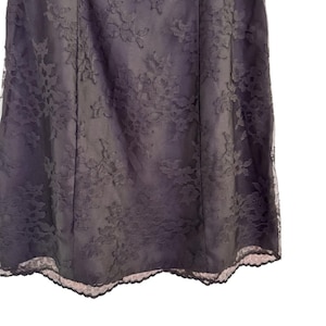 May include: A dark purple skirt with a floral lace overlay. The skirt has a fitted silhouette and a scalloped lace hemline. The lace pattern is detailed and covers the entire skirt, creating a textured look.