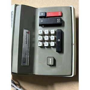 May include: A vintage ITC Citizen 7 calculator in grey with white keys. It has a red 'total' button, a black subtraction button, and a 'clear' button. The display shows numbers from 0 to 7.