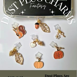 May include: A selection of USB-C dust plug charms featuring designs like a squirrel, acorn, leaf, heart, flower, and pumpkin. The charms are in gold, orange, brown, and white. The image includes the text "Dust Plug Charms" and "USB-C Charm."