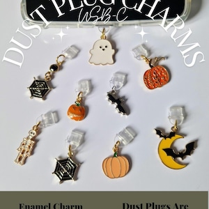 May include: A selection of Halloween-themed enamel charm dust plugs. The charms feature a ghost, pumpkins, bats, a spider web, a skeleton, and a moon with bats. The image text reads "Dust Plug Charms" and "Enamel Charm USB-C".