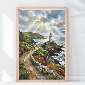 Puede incluir: Pintura a la acuarela de un paisaje costero con un faro en un acantilado rocoso. Un camino sinuoso conduce al faro, con colinas verdes y el océano visible. El cielo está lleno de nubes dramáticas y rayos de sol. La obra de arte está enmarcada en un marco de madera clara.