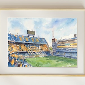 Puede incluir: Pintura a la acuarela de un estadio con asientos azules y amarillos y la palabra "BOCA" visible. La obra de arte está enmarcada en un marco de madera clara, con un campo verde y un cielo azul.