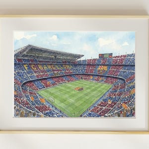 Puede incluir: Impresión en acuarela de un estadio de fútbol, con un campo verde y gradas llenas de espectadores. La arquitectura del estadio es detallada, con el nombre del equipo "FC BARCELONA" visible. La obra está enmarcada en un marco de madera clara.