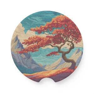 May include: Circular car coaster depicting a stylized landscape with a vibrant orange tree set against mountains and a blue sky. The coaster has a small notch for easy removal and is designed to fit in a car's cup holder.