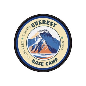 Könnte beinhalten: Ein runder, blauer und weißer Patch mit schwarzen Nähten. Der Patch zeigt ein stilisiertes Bild des Mount Everest mit dem Text "EVEREST BASE CAMP" und "17,098 FEET 5,364M NEPAL".