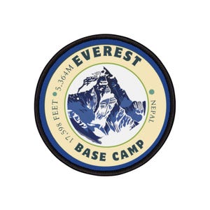 May include: A round, blue and white patch with black stitching. It features a stylised image of Mount Everest with the text "EVEREST BASE CAMP" and "17,598 FEET 5,364M NEPAL".