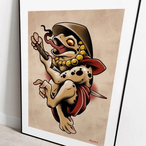 Puede incluir: Impresi&oacute;n enmarcada estilo tatuaje que presenta una criatura parecida a una rana con sombrero, collar y capa roja, sosteniendo una espada. La rana tiene manchas negras y una lengua larga. El fondo es beige.