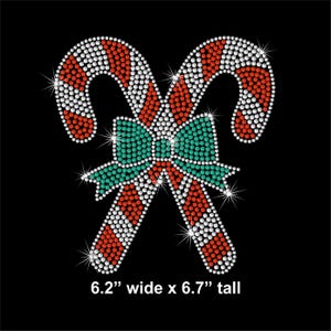 May include: Two rhinestone candy canes with red and white stripes and a teal bow, set against a black background. The design is 6.2 inches wide and 6.7 inches tall. The image sparkles with starburst effects.