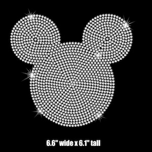 May include: A white rhinestone design of Mickey Mouse's head, 6.6 inches wide by 6.1 inches tall.