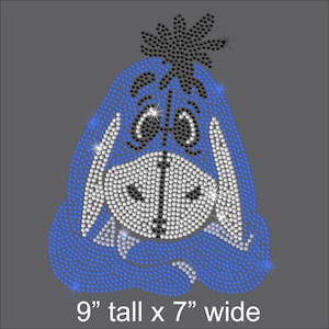May include: A blue, white, and black rhinestone iron-on design of a cartoon donkey with a flower on its head. The design measures 9 inches tall by 7 inches wide.