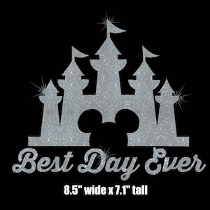 May include: Silver glitter iron-on design featuring a silhouette of Cinderella's castle with Mickey Mouse ears in the center and the text "Best Day Ever" below. The design measures 8.5 inches wide by 7.1 inches tall.