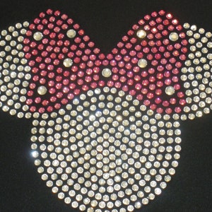 May include: A pink and white rhinestone design in the shape of a Mickey Mouse head.