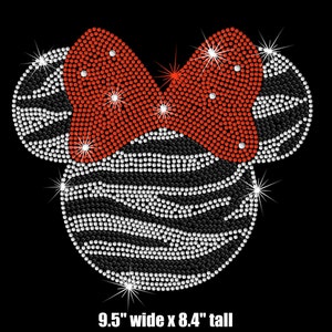 May include: A black and white zebra-print Minnie Mouse ears design with a red bow, made with rhinestones. The design is 9.5 inches wide and 8.4 inches tall.