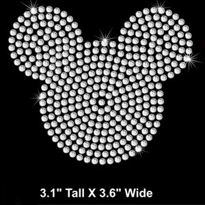 May include: A silver rhinestone design in the shape of Mickey Mouse's head. The design is 3.1 inches tall and 3.6 inches wide.
