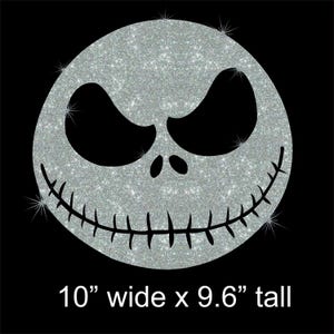 May include: A silver glitter Jack Skellington face on a black background. The design is 10 inches wide and 9.6 inches tall. The face has large black eyes, a stitched smile, and a round shape.