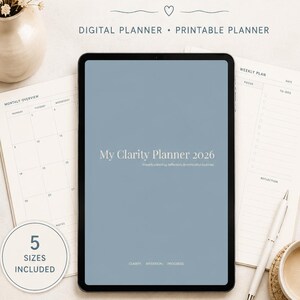 Könnte beinhalten: Ein digitaler und druckbarer My Clarity Planner 2026 auf einem Tablet-Bildschirm mit blauem Hintergrund. Der Planer enthält Abschnitte für Monatsübersicht, Wochenplan, Fokus, Aufgaben und Reflexion. Ein weißer Stift liegt daneben.