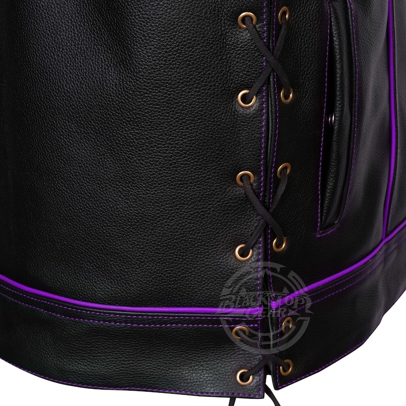 May include: Close-up of a black leather garment with purple stitching and accents. Features a laced closure with gold-colored eyelets and a small pocket. The edges are trimmed with purple stitching.