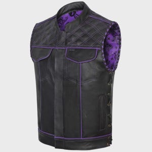 May include: Black leather vest with purple stitching and accents. Features a quilted shoulder design and two front pockets. The interior lining is a purple paisley pattern. Side laces provide an adjustable fit.