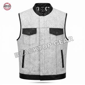 May include: A sleeveless vest featuring a white and gray snakeskin pattern with black leather trim on the collar, armholes, pocket flaps, and hem. The vest includes two chest pockets and two vertical side pockets, with the text BLACKTOP GEAR visible.