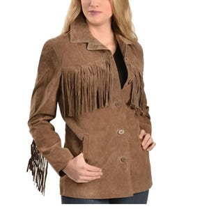 May include: A brown suede jacket with fringe detailing on the chest, sleeves, and back. The jacket has a button-up front, a notched collar, and two front pockets. The jacket is a classic Western-inspired style.