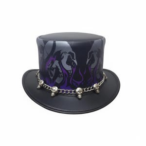 Op de afbeelding: Een zwarte hoge hoed met een schedel- en vlamontwerp in grijs en paars. Een zilveren ketting met schedelbedels omcirkelt de basis van de hoed. De hoed heeft een brede rand en een cilindrische kroon.