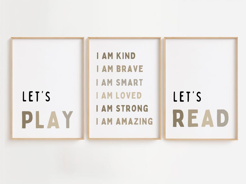 May include: Three framed prints with positive messages. The left print says "LET'S PLAY" in black and taupe. The centre print lists affirmations. The right print says "LET'S READ" in black and taupe. All are in light wood frames.