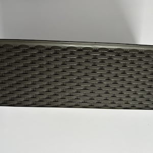 May include: A dark brown rectangular basket with a woven design. The basket has a textured surface and a smooth rim. The basket is empty and is placed on a white surface.