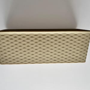 May include: A rectangular storage basket with a woven pattern in a light beige colour. The basket has a slightly flared top edge and is designed for organizing items. The basket is made of a durable material.