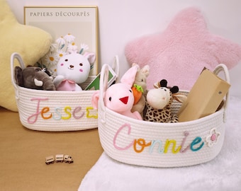 May include: Two white rope baskets with colorful embroidered names "Jesse" and "Connie". The baskets are filled with stuffed animals, including a giraffe, elephant, bunny, and a carrot.