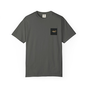 Puede incluir: Una camiseta de manga corta color gris carbón con un pequeño gráfico cuadrado negro en el pecho izquierdo. El gráfico contiene un icono de estrella dorada y el texto "STAR FAST" en una fuente estilizada. La camiseta tiene cuello redondo.