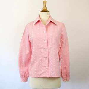 May include: A pink and white gingham button-up shirt with a white lace collar and cuffs. The shirt has a fitted silhouette and long sleeves.