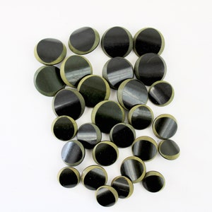 May include: A collection of 20 round, black and green buttons. The buttons have a half-circle design with a black center and a green outer edge.