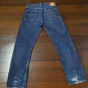 May include: A pair of blue denim jeans with distressed details and a brown leather patch on the back.