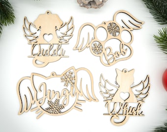 May include: Four wooden pet-themed Christmas ornaments. Each ornament features a pet silhouette with angel wings, a heart, and a name. The ornaments include a dog, paw print, cat, and cat silhouette.