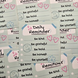 May include: A set of five pastel blue and green reminder cards with pink hearts, a smiley face, and a flower. The cards have the text "Daily Reminder" and a list of positive affirmations: "Be kind", "Be grateful", "Be bold", "Be honest", and "Be yourself".