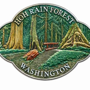 May include: An oval-shaped metal plaque featuring a relief scene of the Hoh Rain Forest in Washington. The design depicts tall evergreen trees, a wooden bridge, and a fallen log, with the text HOH RAIN FOREST and WASHINGTON in raised letters.