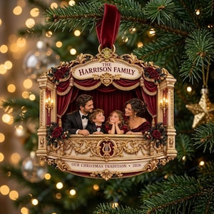 Puede incluir: Un adorno para árbol de Navidad con forma de palco de teatro con cortina de terciopelo rojo. Incluye un retrato familiar, el texto THE HARRISON FAMILY y OUR CHRISTMAS TRADITION 2026. El marco es dorado con rosas rojas y un emblema de lira.