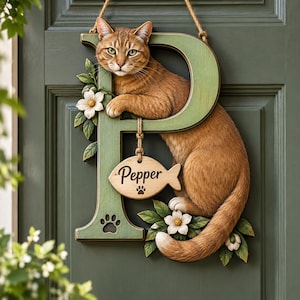 May include: A decorative wooden letter P in a muted green finish, featuring a sculpted orange tabby cat resting on the top bar. A small wooden fish-shaped sign hangs from the letter, inscribed with the name Pepper and a paw print icon.