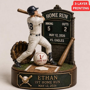 Könnte beinhalten: Eine Baseball-Figur eines Spielers in gestreifter Uniform beim Schlag. Der Sockel zeigt den Namen ETHAN, 1ST HOME RUN und MAY 12, 2026. Eine Anzeigetafel zeigt HOME RUN, INNING 5, OUTS 2, MAY 12, 2026, VS. EAGLES. Ein Baseball und ein Handschuh sind enthalten.