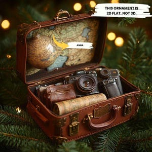 Adorno plano 2D de maleta de viaje vintage: minicámara y mapa, decoración navideña para trotamundos.